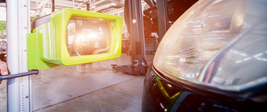 Worker checks and adjusts the headlights of a car's lighting system