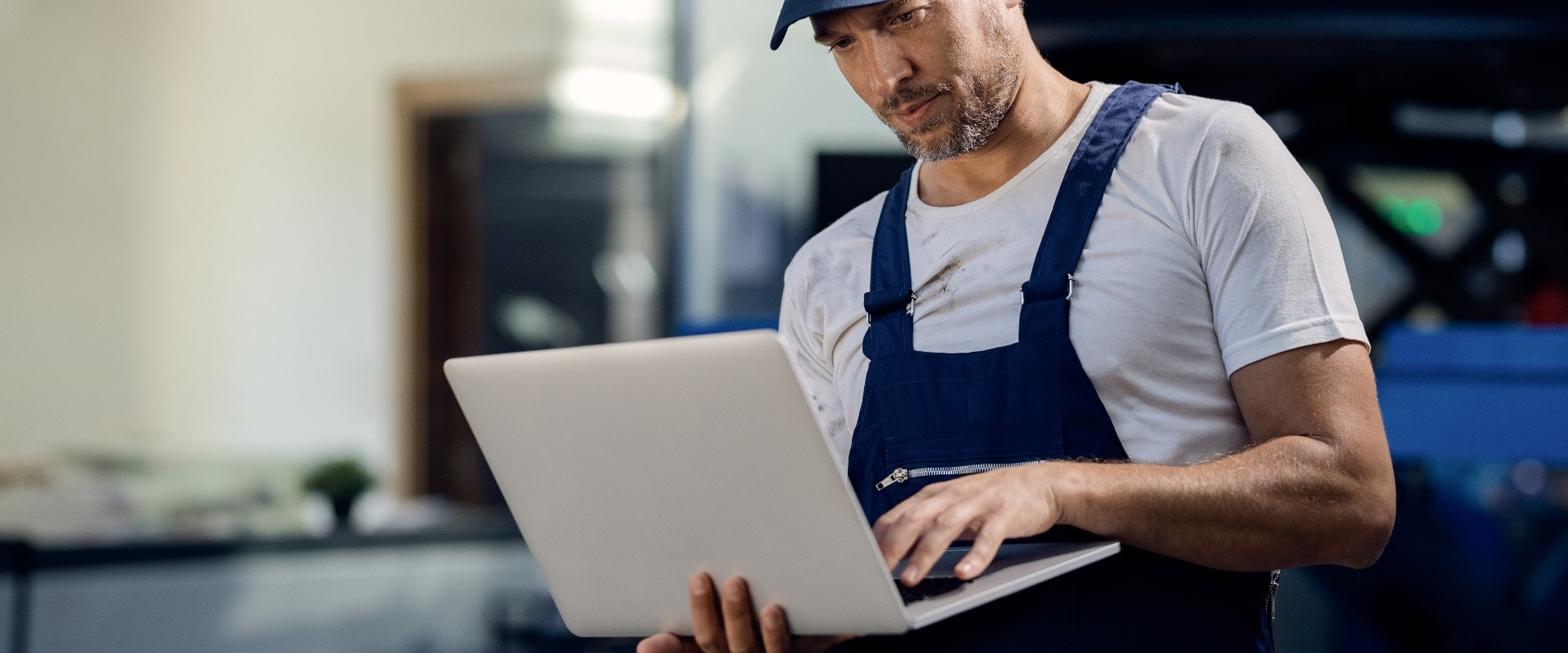Mid adult repairman using laptop at car workshop.